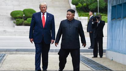 Le dirigeant nord-coréen Kim Jong-un et le président américain Donald Trump traversent la ligne de démarcation militaire séparant la Corée du Nord de la Corée du Sud, au sein de la Zone démilitarisée (DMZ), le 30 juin 2019.