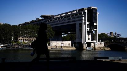 Une femme marche près du bâtiment du Ministère de l’Économie et des Finances français, également connu sous le nom de Bercy, et de la rivière Seine à Paris, France, le 11 août 2026.