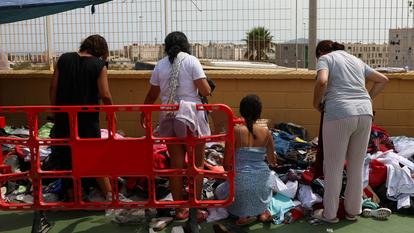 Des migrantes choisissent des vêtements donnés dans le quartier El Príncipe de l’enclave espagnole de Ceuta en Afrique du Nord, le 19 août 2026.