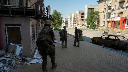 Des membres des forces armées de la 93e brigade mécanisée séparée Kholodnyi Yar des forces armées ukrainiennes marchent sur une rue endommagée dans la ville de front de Druzhkivka, au milieu de l’attaque de la Russie contre l’Ukraine, dans la région de Donetsk, Ukraine, le 10 août 2026.