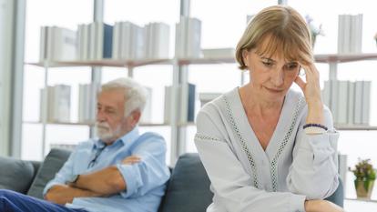 Sad mature woman sitting away from her husband after having quarrel