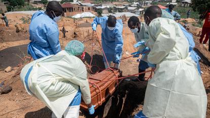 Des équipes de la Fédération internationale des Sociétés de la Croix-Rouge et du Croissant-Rouge transportent, au cimetière de Mbiyo, le corps d’un quatrième orphelin décédé des suites de la maladie à virus Ebola dans un orphelinat de Bunia, dans la province de l’Ituri, le 19 juin 2026.