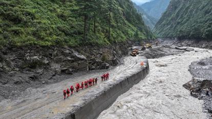 Une vue de drone des pompiers effectuant des opérations de recherche et de sauvetage sur une route endommagée menant au port de Gyirong, Chine, le 28 août 2026.