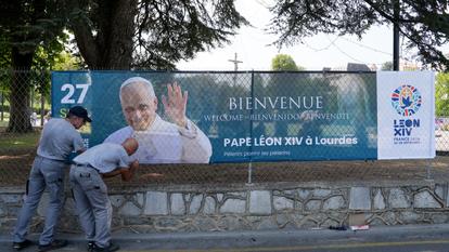 Les équipes techniques du sanctuaire de Lourdes installent des bannières de bienvenue, aux abords du site.