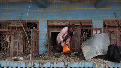 Une femme cherche ses affaires dans une maison remplie de boue, à la suite de crues soudaines et de glissements de terrain, à Devighat, au Népal, le 29 août 2026.