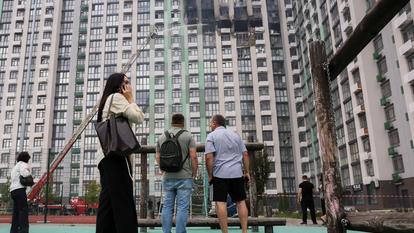 Les passants regardent des pompiers au travail sur le site d’une frappe de drone russe sur un immeuble résidentiel, à Kiev, le 1er septembre 2026.
