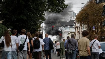 Des passants observent les dégâts d’une frappe russe sur le siège du SBU, à Kiev.