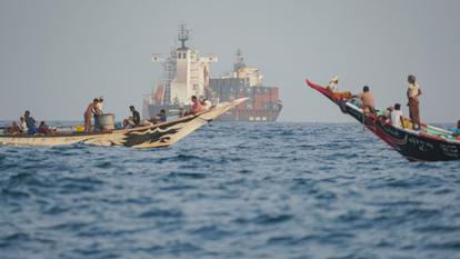 Des personnes naviguent près de porte-conteneurs au mouillage, à proximité du détroit de Bab el-Mandeb, au large des côtes du Yémen, dans le golfe d’Aden, le 6 août 2026.