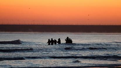 Un groupe de migrants patauge dans l’eau pour monter à bord d’un canot gonflable avant de quitter la côte nord de la France dans une tentative de traverser la Manche pour atteindre la Grande-Bretagne, depuis la plage de Petit-Fort-Philippe à Gravelines, près de Calais, France, le 6 septembre 2026.