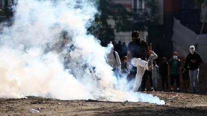 Un manifestant masqué tente de frapper un obus de gaz lacrymogène lors d’une manifestation d’élèves de lycée à Aubervilliers, près de Paris.