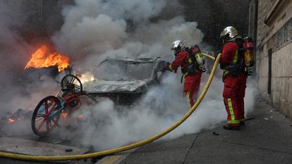 les pompiers éteignent une voiture en feu au milieu des violences lors d’une journée de manifestations contre le coût de la vie, à Paris le 17 octobre 2026.