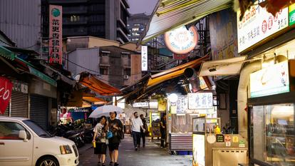 Des passants traversent un marché sous la pluie à l’approche du typhon Champi, à Taipei, le 22 octobre 2026.