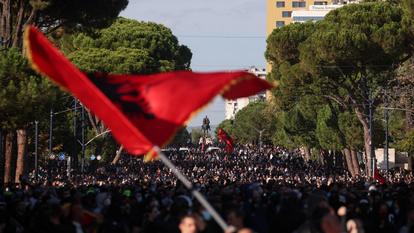 Une personne agite un drapeau albanais alors qu’une foule de manifestants se rassemble près du Monument de Skanderbeg lors d’une protestation anti-gouvernementale par des étudiants à Tirana, Albanie, le 24 octobre 2026.