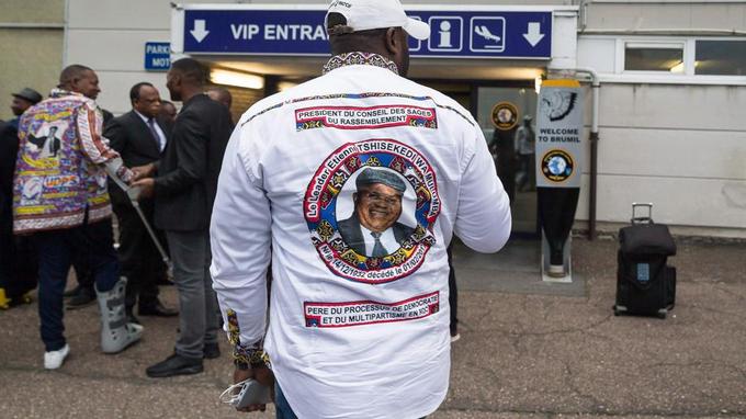 Un homme portant le portrait d'Étienne Tshisekedi sur sa chemise, se tient devant l'aéroport de Melsbroek après du rapatriement des dépouilles du dirigeant de l'opposition congolaise.