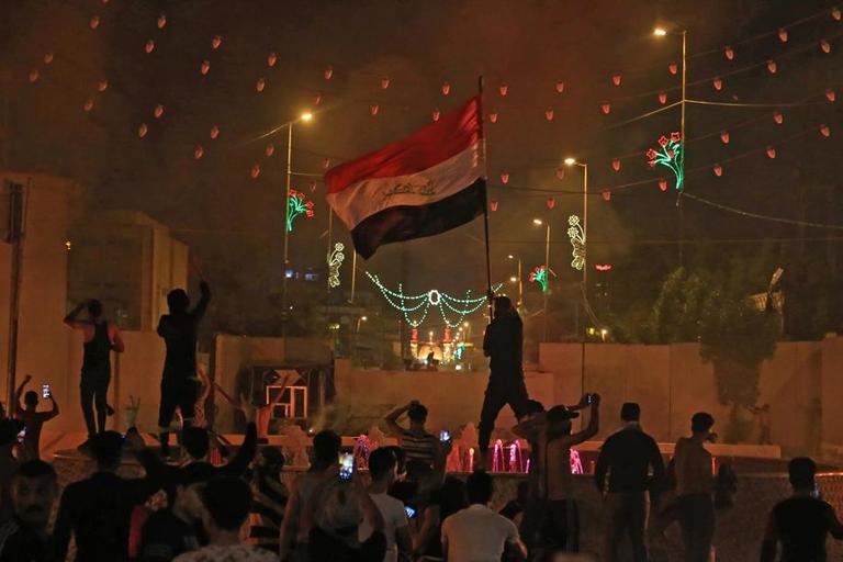 Un protestataire agite un drapeau irakien, le vendredi 25 octobre à Karbala, une ville chiite au sud de Bagdad