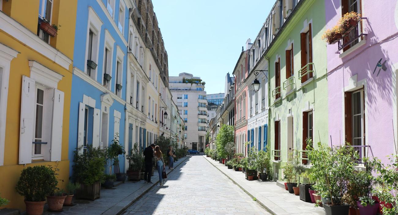La rue Crémieux, dans le 12e arrondissement de Paris, présente de petites maisons colorées jaune, vert, bleu, rose.