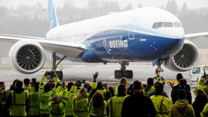 Des employés de Boeing et d’autres personnes célèbrent le retour du Boeing 777X dans un hangar après son premier vol d’essai.