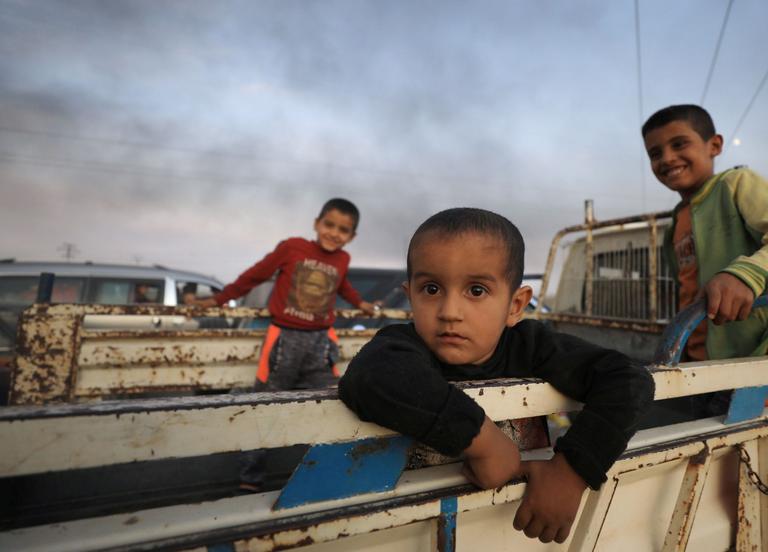 Des enfants sont installés à l’arrière d’un camion fuyant la ville de Ras al Ain, le mercredi 9 octobre.
