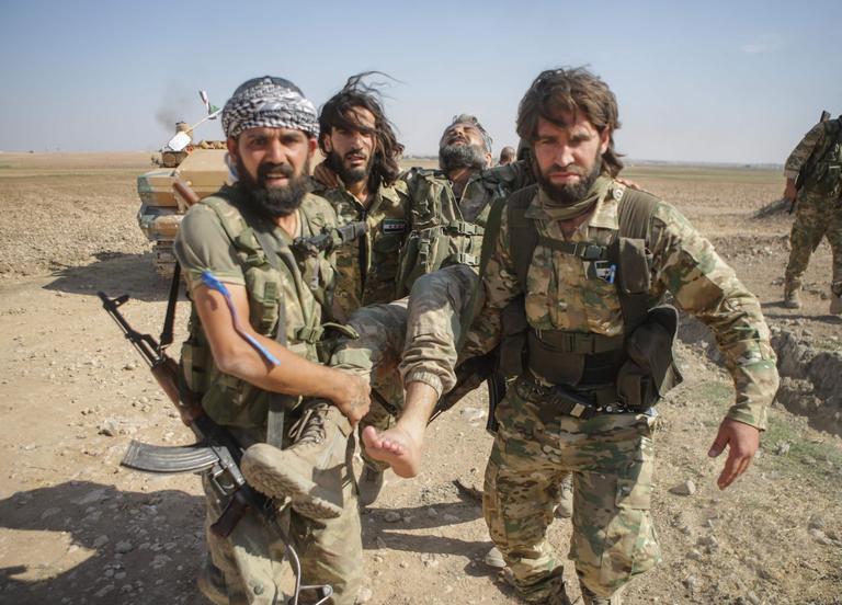 Des combattants syriens soutenus par les Turcs transportent un homme blessé, près d’Al Abyad, le samedi 12 octobre.