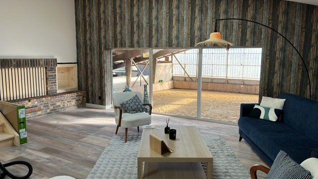 Dans ce bâtiment entièrement rénové de 350 m², près de Caen (14), sept étudiants cohabiteront avec une vingtaine de chevaux. (Vue sur le manège en second plan).