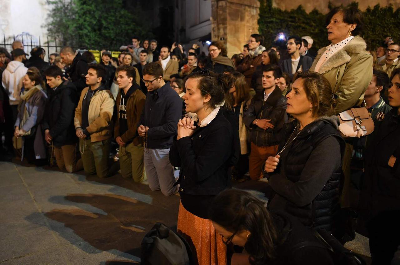 Des gens prient dans la rue en regardant les flammes de l'incendie de Notre-Dame de Paris. Éric Feferberg pour l'AFP  