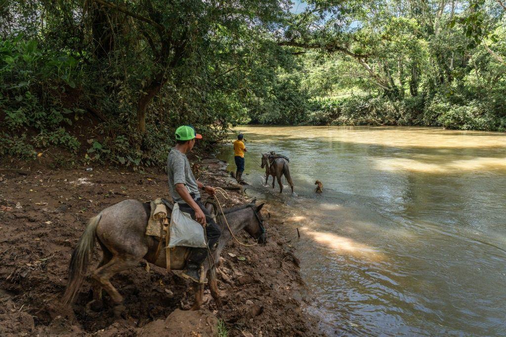 Des habitants de la localité d'El Limon traversent le fleuve Indio, le 21 novembre 2023. Un projet de barrage menace de noyer une partie de la commune et de forcer 2000 personnes à se déplacer. Walter Hurtado/Bloomberg /via Getty Images