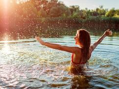 Une femme se baigne dans une rivière. Comment savoir si l'eau de baignade est propre ?
