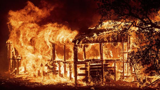  In this photo of Thursday, July 26, 2018, a structure burns then that the "Carr" light rolls along Route 299 near Redding, California 