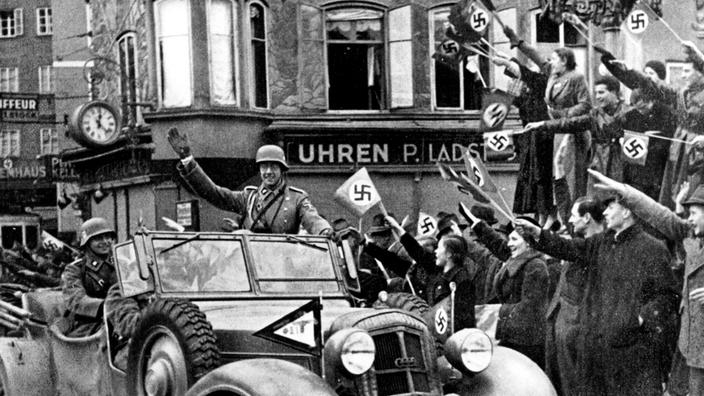 As tropas alemãs que invadiram a Áustria em Março de 1938 são aplaudidas pela multidão com pequenas bandeiras com a suástica.' Autriche en mars 1938 sont acclamées par la foule avec des petits drapeaux avec la croix gammée.