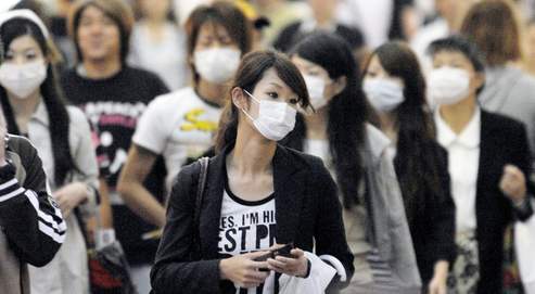 Ces passants d'une rue commerçante de Kobé portent presque tous des masques. Les industriels du secteur enregistrent des hausses records à la Bourse de Tokyo.