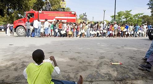 Des habitants de Port-au-Prince font la queue pour recevoir de l'eau potabledistribuée par un camion de pompiers, mercredi dans la capitale haïtienne.
